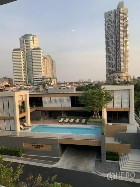 Detached House for sale in Yan Nawa, Bangkok - Community clubhouse with swimming pool and sun loungers facing the Bangkok skyline.
