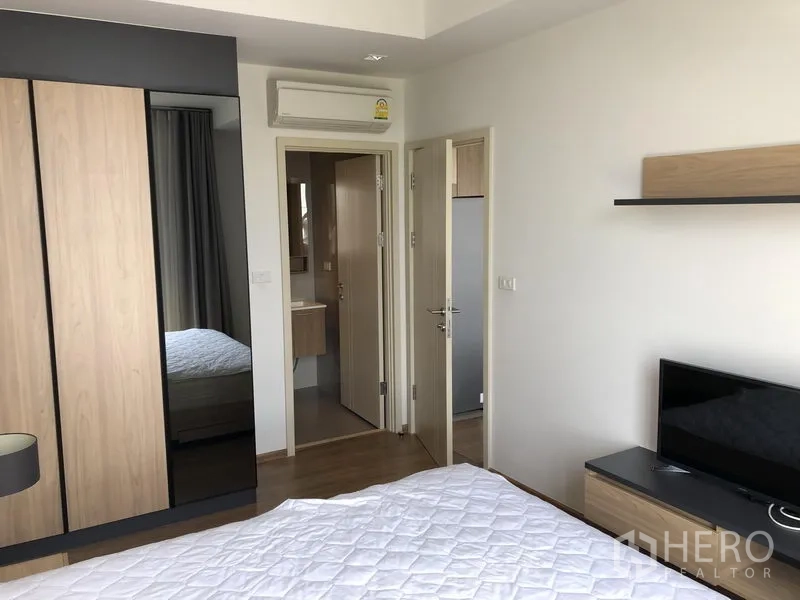 Condominium for rent in Watthana, Bangkok - Bedroom with wardrobe, TV stand, and ensuite bathroom access.