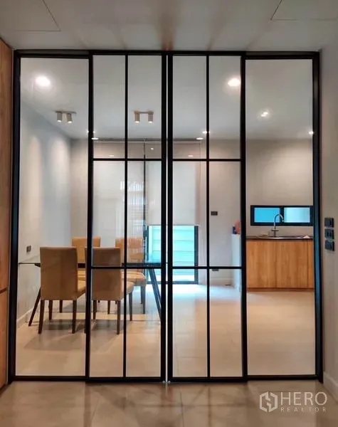 Townhouse for rent in Suan Luang, Bangkok - Black-framed glass partition opening to the dining room and light-wood kitchen