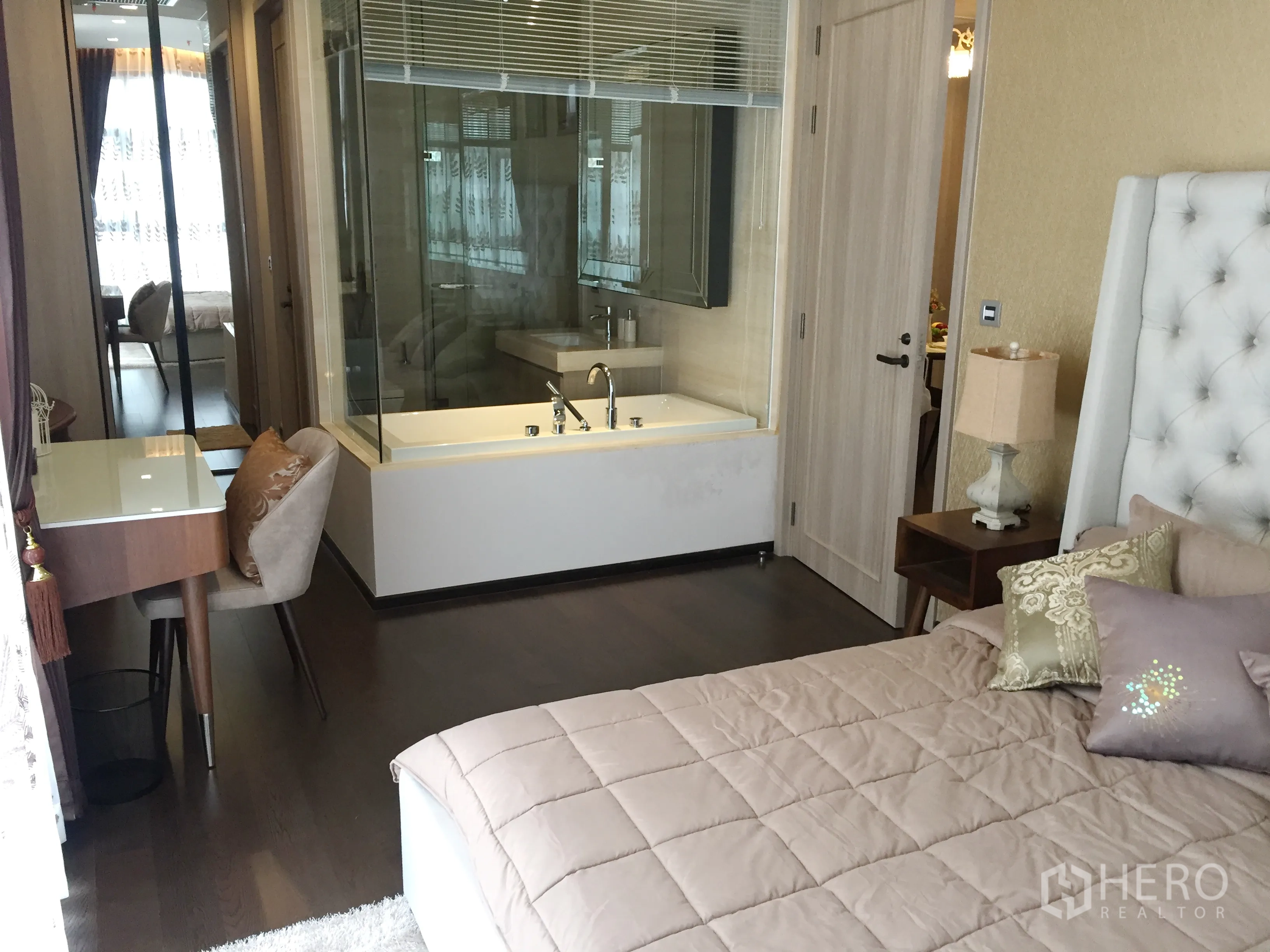 Condominium for rent in Watthana, Bangkok - Bedroom with glass-walled bathroom featuring a soaking bathtub, vanity, and study desk nearby.