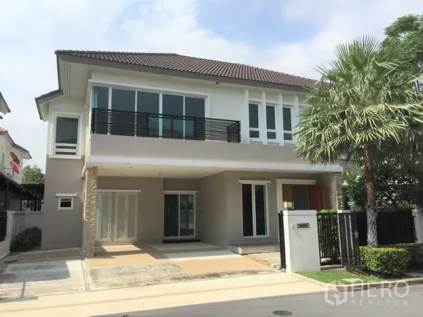 บ้าน ให้เช่าในSaphan Sung, Bangkok - บ้านเดี่ยวสองชั้นสไตล์โมเดิร์น มีระเบียง หลังคากระเบื้อง พร้อมรั้วและที่จอดรถใต้ร่มปาล์ม