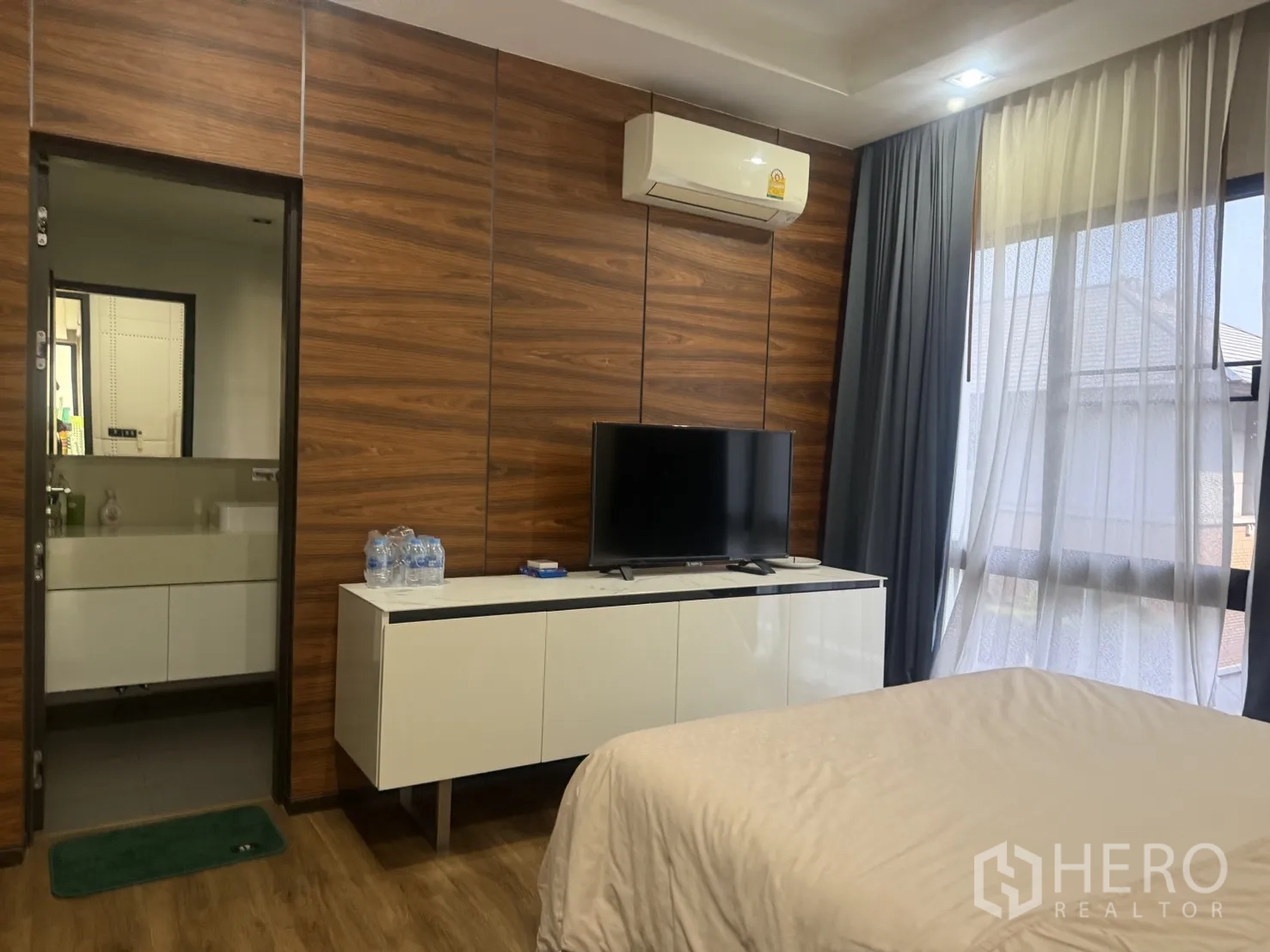 Detached House for rent in Bang Kapi, Bangkok - Cozy bedroom with TV console, wood wall panels, and ensuite doorway.
