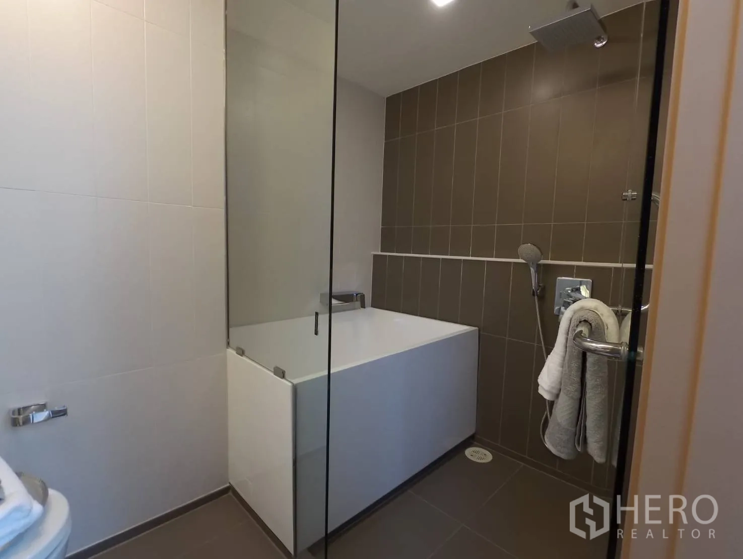Condominium for rent or sale in Khlong Toei, Bangkok - Bathroom with glass partition, deep soaking tub, and rainfall shower.