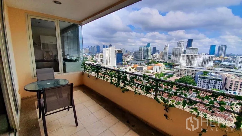 Condominium for rent in Watthana, Bangkok - Covered balcony with table and chairs overlooking an open Bangkok skyline view.