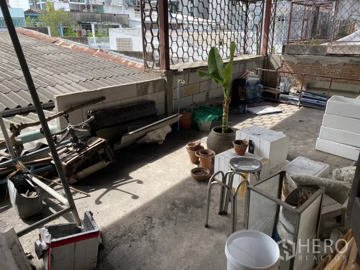Shophouse for rent in Khlong Toei, Bangkok - Partially covered rooftop terrace used for storage with urban outlook.