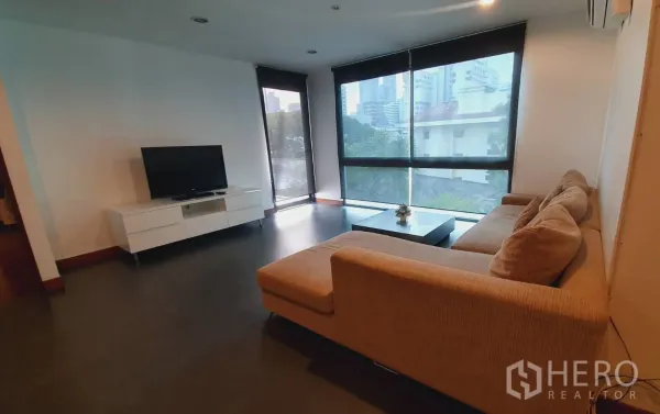 公寓 出租在Khlong Toei, Bangkok - 客厅配L型沙发、电视柜与落地转角窗，眺望城市景观。