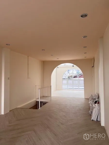 Shophouse for rent or sale in Watthana, Bangkok - Long open hall with recessed lighting and an archway leading to a front terrace.