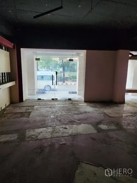 零售空间 出租在Khlong Toei, Bangkok - 空置店铺内部，面向临街玻璃双开门，水泥地面与深色天花。