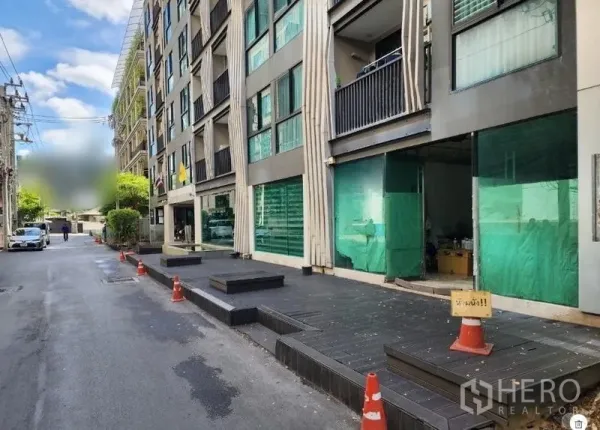 零售空间 出租 - 静街上的一排一层店铺，绿色玻璃门面与宽阔人行平台。