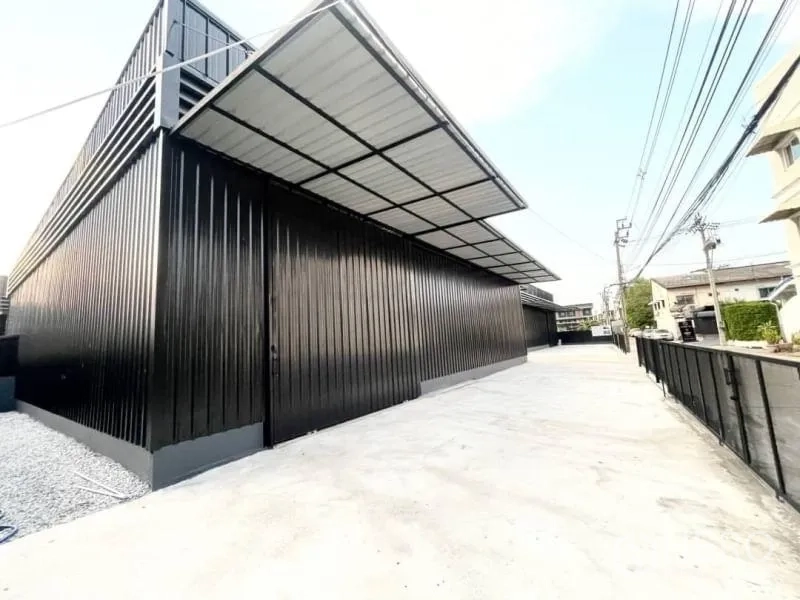 Warehouse for rent in Lat Phrao, Bangkok - Modern black metal warehouse exterior in Lat Phrao with covered loading canopy and a wide concrete driveway.