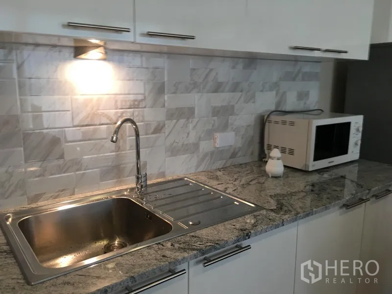 Condominium for rent in Watthana, Bangkok - Modern kitchenette with stainless sink, granite countertop and subway-tile backsplash.