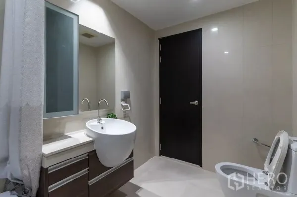 Condominium for rent - Spacious bathroom angle showing vanity, toilet and neutral tiled walls.