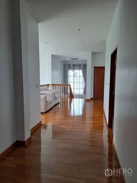 独立式住宅 出租在Prawet, Bangkok - 二楼走廊铺木地板，通向起居区与落地窗。
