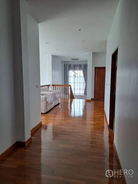 独立式住宅 出租在Prawet, Bangkok - 二楼走廊铺木地板，通向起居区与落地窗。