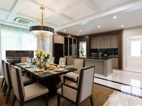 Detached House for rent in Mueang Samut Prakan, Samut Prakan - Spacious dining room with statement chandelier adjoining a full kitchen and island, bright natural light.