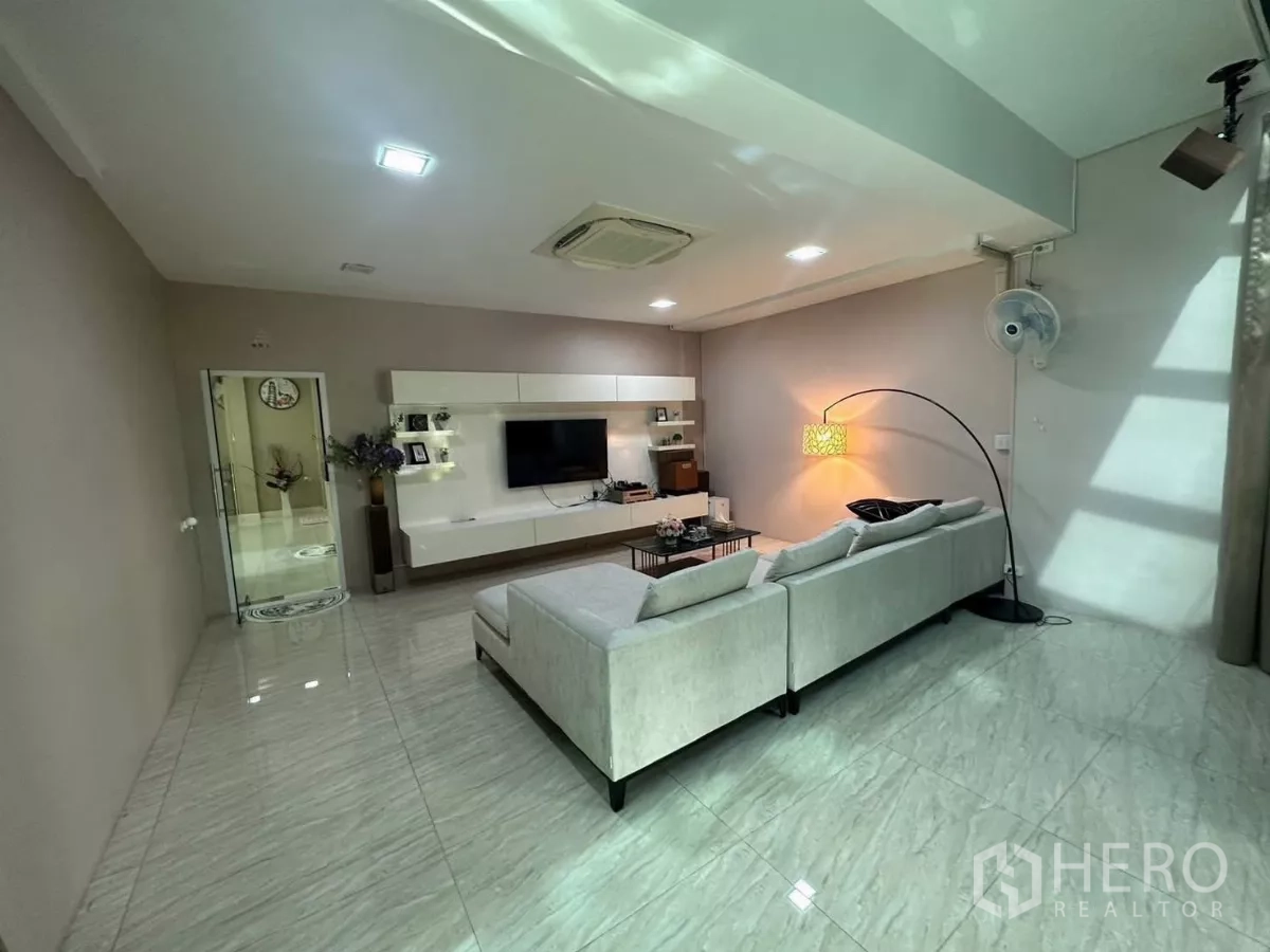 Detached House for rent or sale in Bang Kapi, Bangkok - Media living room with long sectional sofa, feature floor lamp and TV wall.
