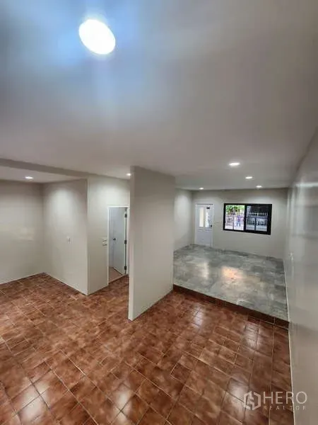 联排别墅 出租在Wang Thonglang, Bangkok - 开放式客厅，错层铺砖地面与筒灯照明。