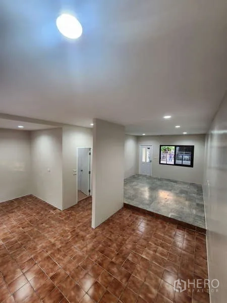 联排别墅 出租在Wang Thonglang, Bangkok - 开放式客厅，错层铺砖地面与筒灯照明。