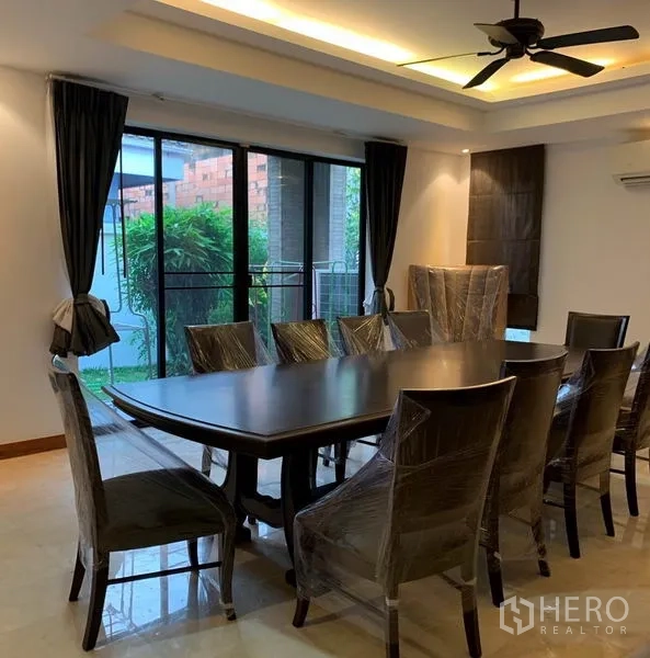Detached House for rent in Din Daeng, Bangkok - Formal dining room with long table, ceiling fan and sliding doors opening to the garden.