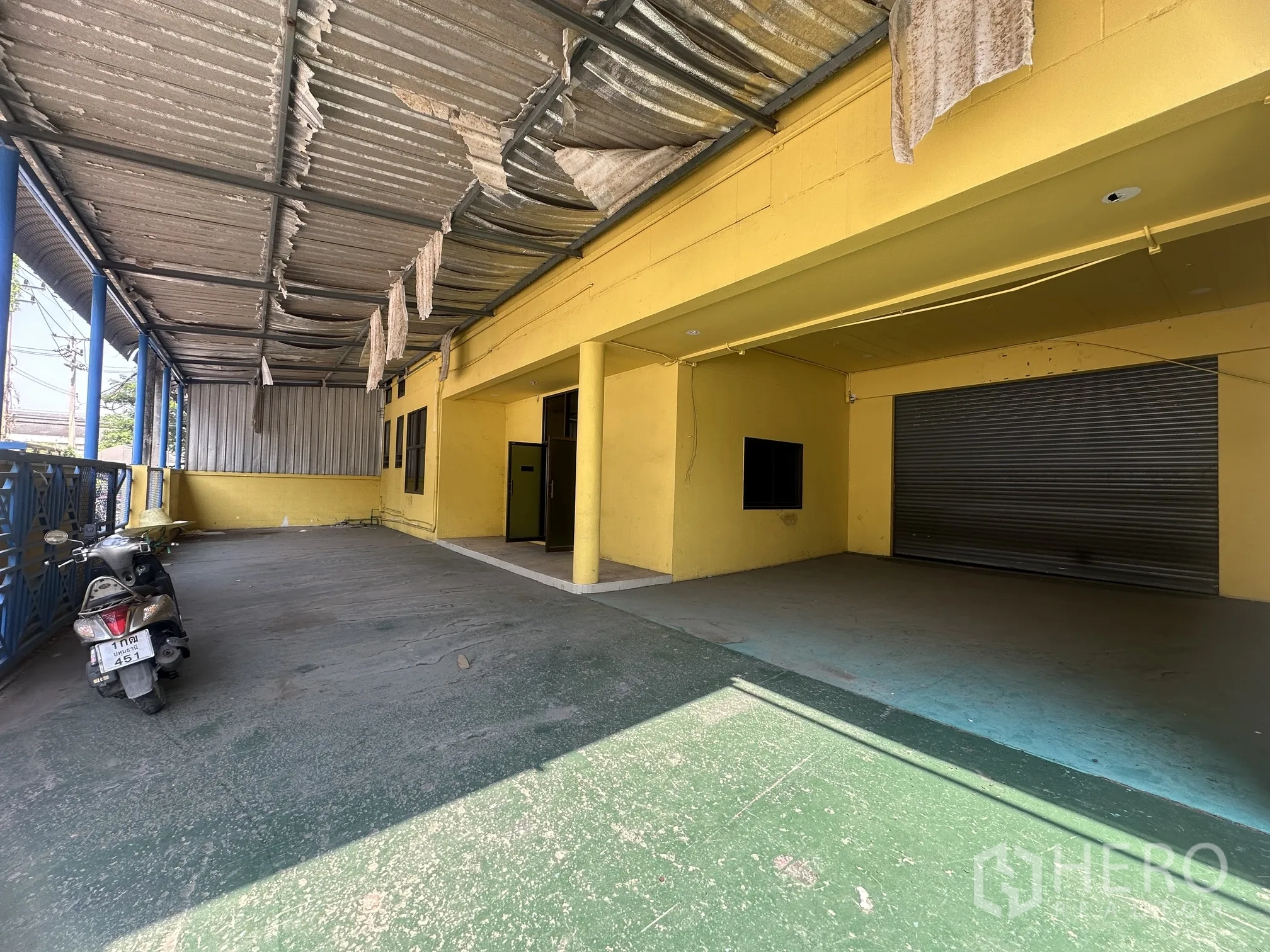 Factory for rent in Lat Lum Kaeo, Pathum Thani - Covered loading area with a corrugated roof, columns, and a large roller shutter door.