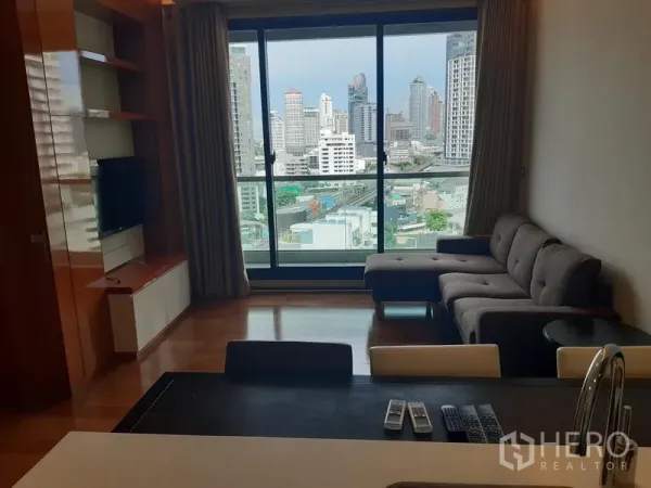 Condominium for rent in Khlong Toei, Bangkok - Living room with floor-to-ceiling windows and Bangkok skyline view.