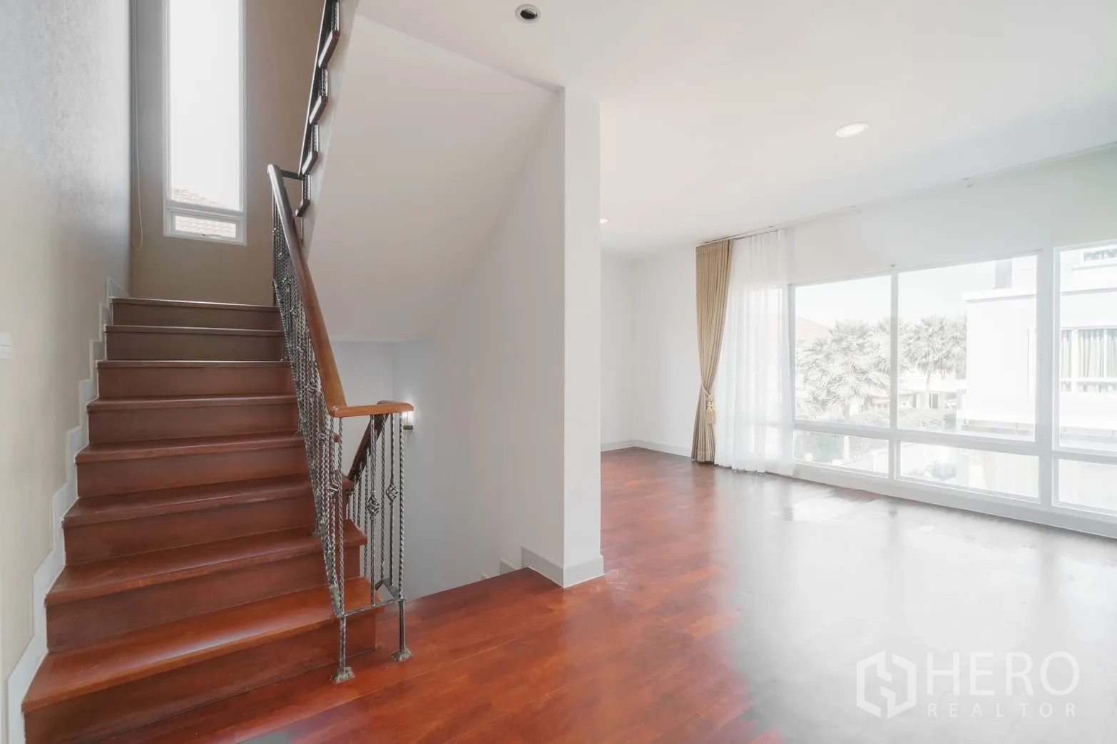 独栋房屋 for rent or sale in Saphan Sung, Bangkok - 楼梯间与家庭起居区，超高窗户与木楼梯。