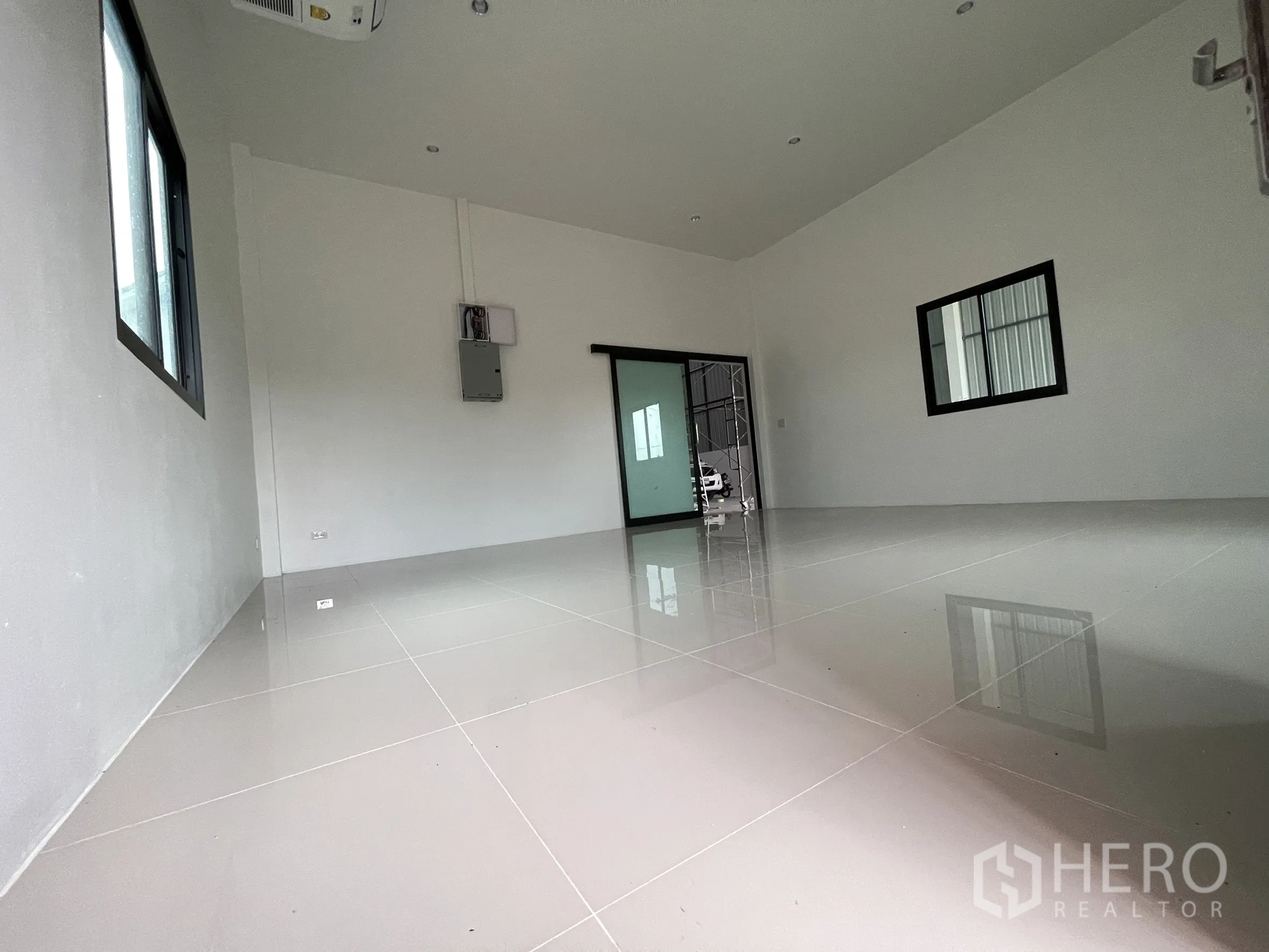 Factory for rent or sale in Lam Luk Ka, Pathum Thani - Bright office room with glossy tiled floor, windows, and sliding door to the warehouse.