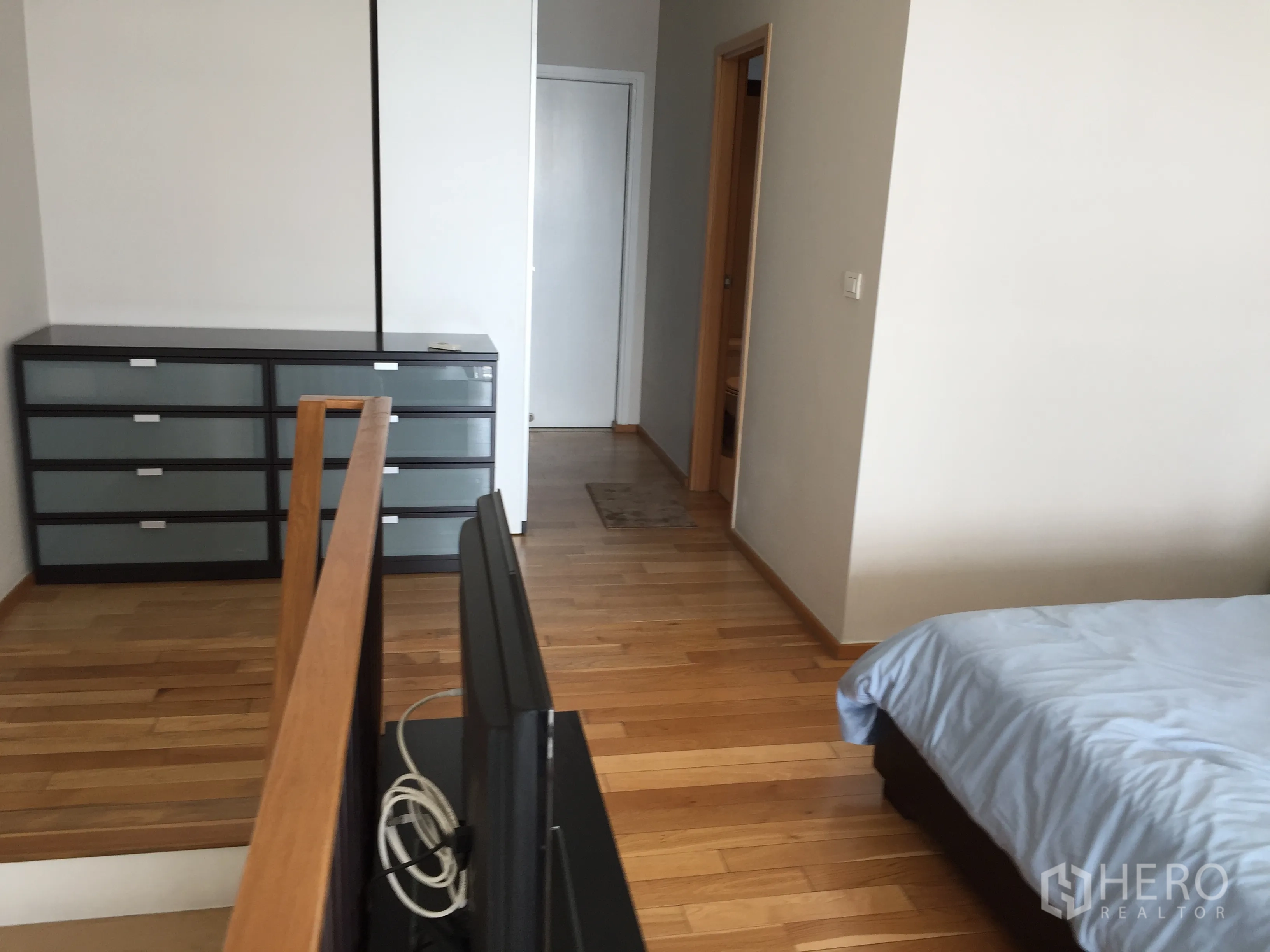 Condominium for rent in Khlong Toei, Bangkok - Mezzanine bedroom area with wood flooring, dresser and access to a bathroom.