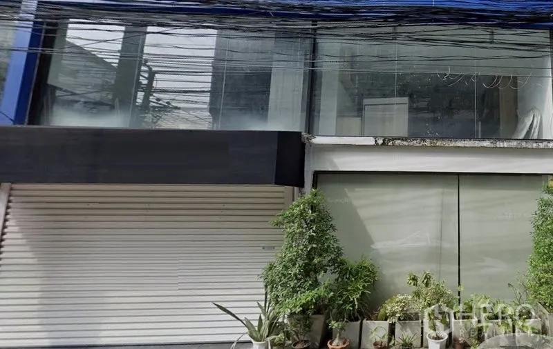 Retail Space for rent in Watthana, Bangkok - Two-storey glass-fronted retail unit with roller shutter and potted plants in Watthana.