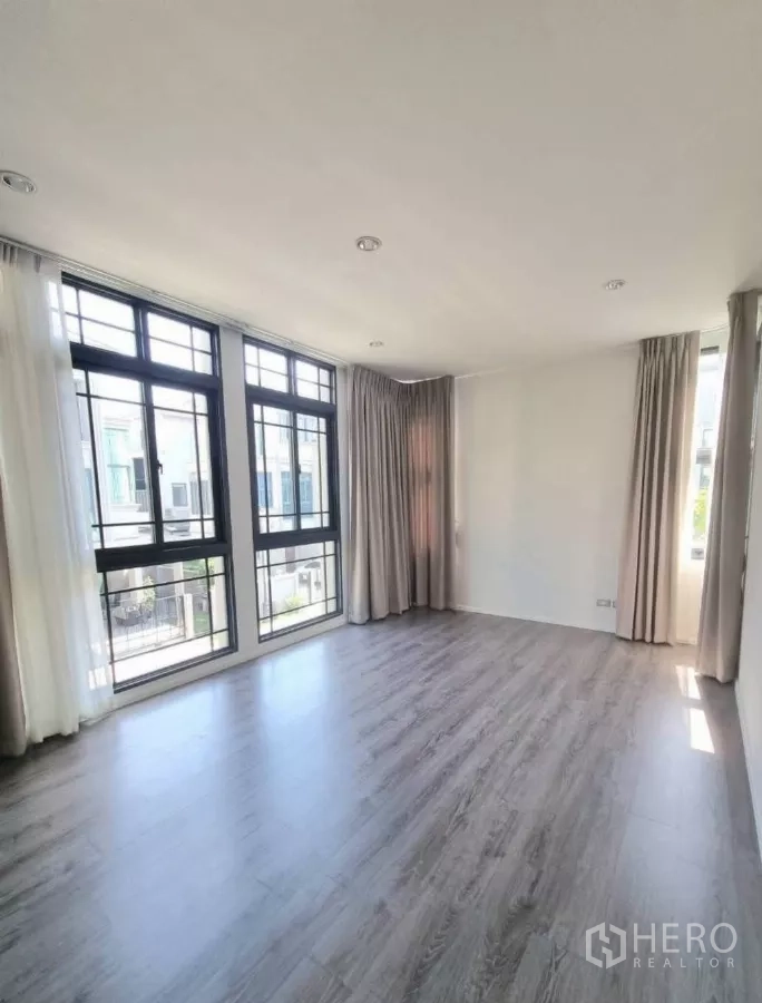 独立式住宅 出售在Prawet, Bangkok - 采光充足的客厅，落地窗与木地板。