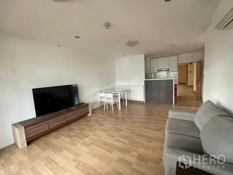 Condominium for rent in Watthana, Bangkok - Spacious lounge leading to a modern kitchenette with ample storage.