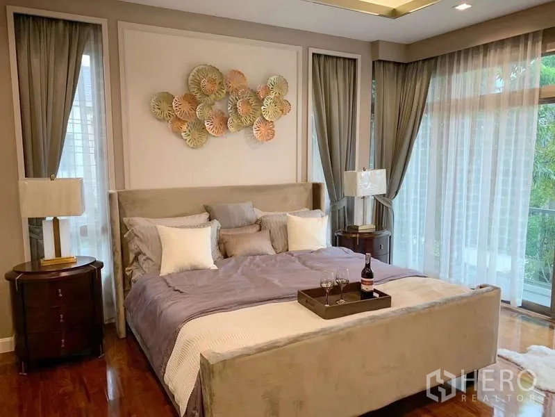 Detached House for rent or sale in Bang Phli, Samut Prakan - Master bedroom with large bed, wall art and corner glass doors to balcony.