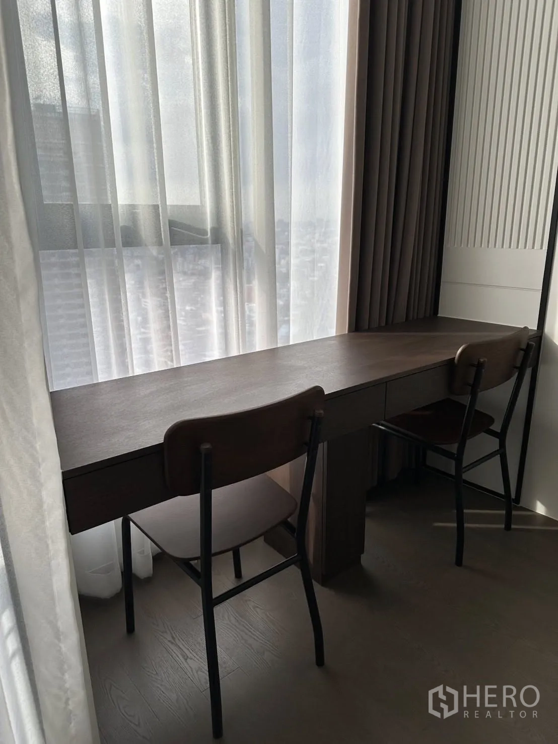 公寓 出租在Bang Rak, Bangkok - 窗边长书桌配两把椅子，轻纱窗帘与城市景色。