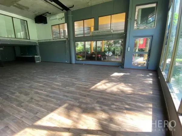 零售空间 出租在Watthana, Bangkok - 明亮展示区，宽幅玻璃门面与侧门入口。