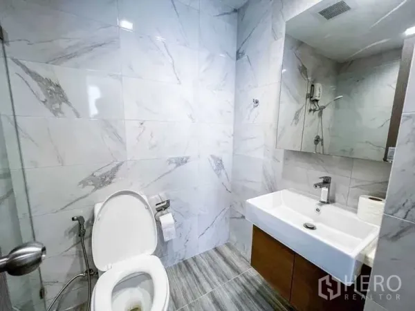 คอนโด ขายในHuai Khwang, Bangkok - ห้องน้ำสมัยใหม่ ผนังลายหินอ่อน อ่างล้างหน้าทรงสี่เหลี่ยมพร้อมกระจกบานใหญ่ และโถสุขภัณฑ์