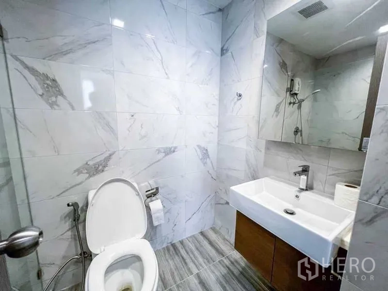 คอนโด ขายในHuai Khwang, Bangkok - ห้องน้ำสมัยใหม่ ผนังลายหินอ่อน อ่างล้างหน้าทรงสี่เหลี่ยมพร้อมกระจกบานใหญ่ และโถสุขภัณฑ์