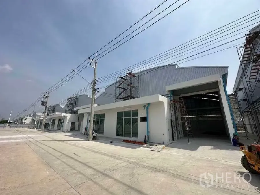 Factory for rent in Khlong Luang, Pathum Thani - Street view of modern factory row with loading bays under a clear sky.