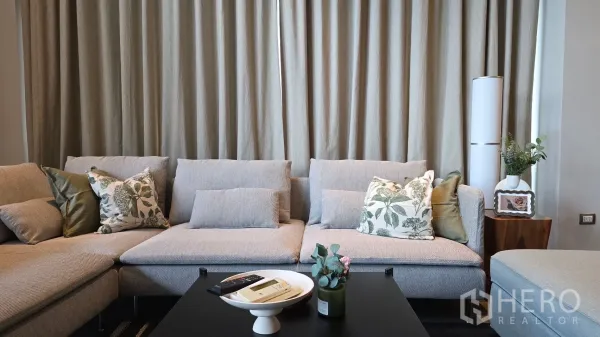 Condominium for rent - Close-up of plush L-shaped sofa with patterned cushions and coffee table.