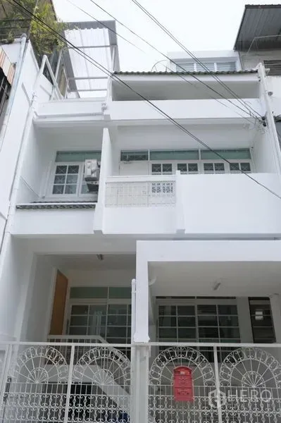 联排别墅 出租在Khlong Toei, Bangkok - 三层白色联排别墅外立面，带围栏车位，位于静巷内。