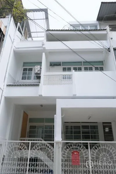 联排别墅 出租在Khlong Toei, Bangkok - 三层白色联排别墅外立面，带围栏车位，位于静巷内。