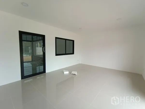 Warehouse for rent or sale in Bang Yai, Nonthaburi - Bright ground‑floor office with white walls, glossy tiled floor, black‑frame glass door and window.