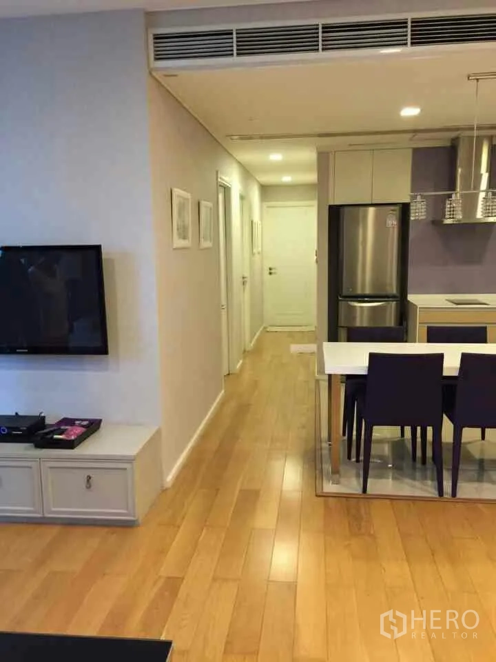 Condominium for rent or sale in Watthana, Bangkok - Open-plan living, dining and kitchen area with wood floors, pendant lights and a stainless refrigerator near Asok BTS.