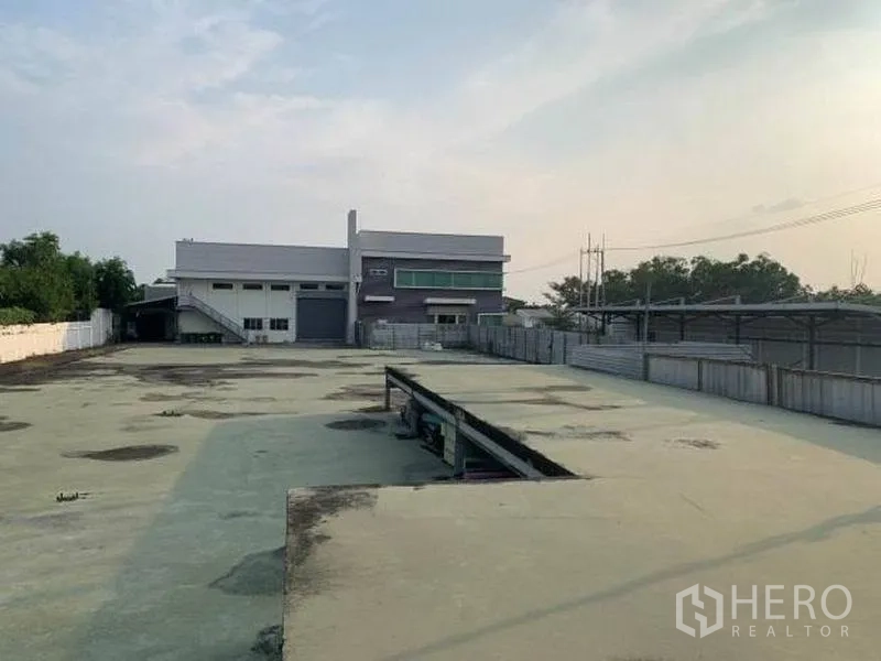 Factory for rent or sale in Wang Noi, Phra Nakhon Si Ayutthaya - Wide concrete yard leading to a modern factory building with offices.