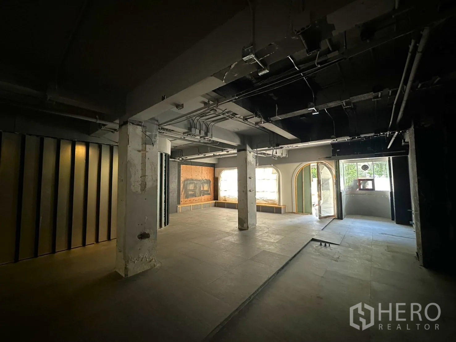 พื้นที่ขายของ for rent in Watthana, Bangkok - มุมมองไปยังหน้าร้าน มีประตูกระจกทรงโค้ง กระจกโชว์ และพื้นยังไม่ตกแต่ง.