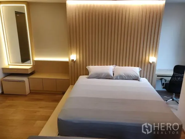 公寓 出租在Ratchathewi, Bangkok - 卧室设平台床与木质格栅背景墙，灯光温暖。