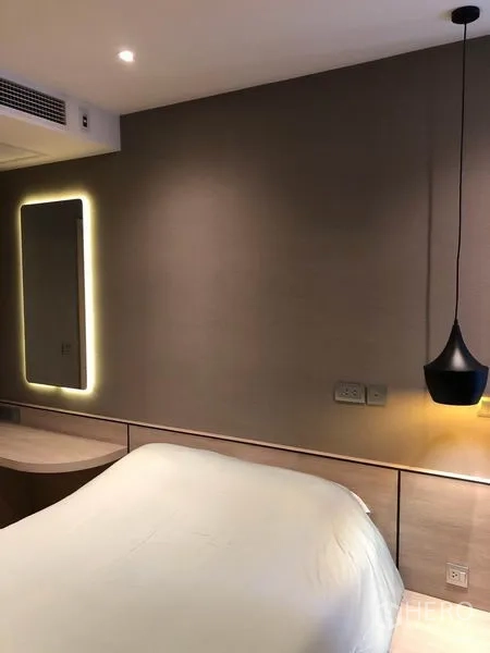 Condominium for rent in Din Daeng, Bangkok - Bedroom wall with backlit mirror, soft lighting, and light-wood headboard.