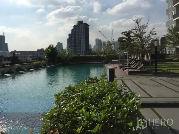 Condominium for rent in Khlong Toei, Bangkok - Resort-style swimming pool with sun loungers, landscaped deck and Bangkok skyline backdrop.