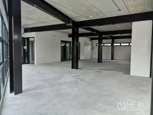 Office Space for rent in Chatuchak, Bangkok - Open-plan shell office with exposed ceiling, black steel beams, concrete flooring and large glass walls.