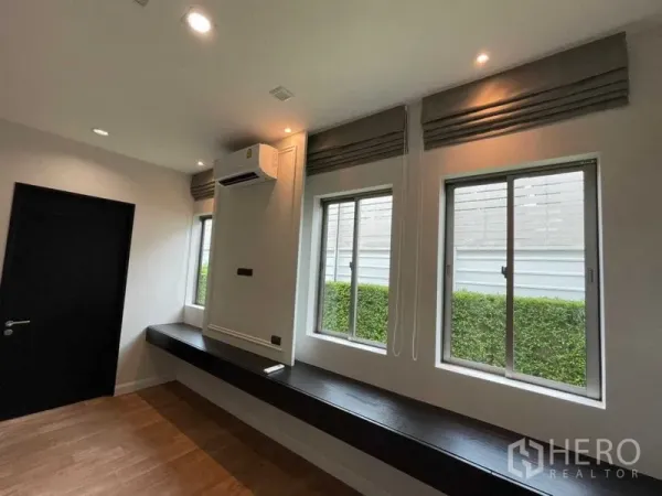 独立式住宅 出租或出售在Lat Krabang, Bangkok - 带三扇窗的房间，百叶帘与壁挂空调，长条内置台面，窗外绿篱。