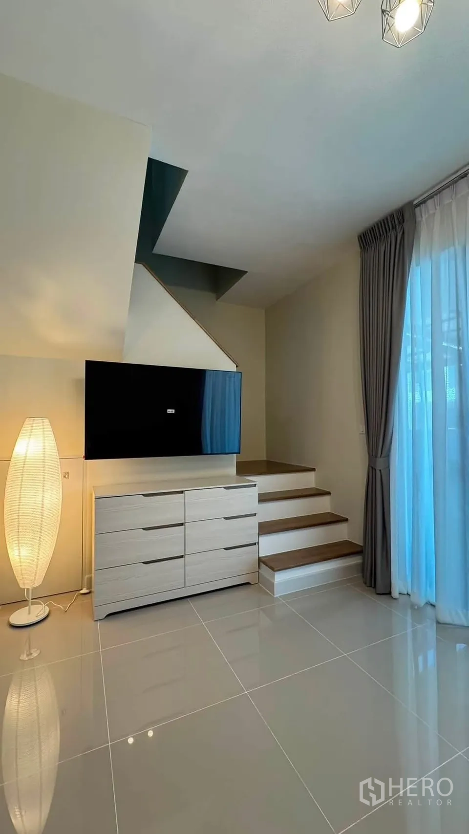 联排别墅 for rent in Bang Phli, Samut Prakan - 客厅设壁挂电视与抽屉柜，楼梯与推拉门相邻。